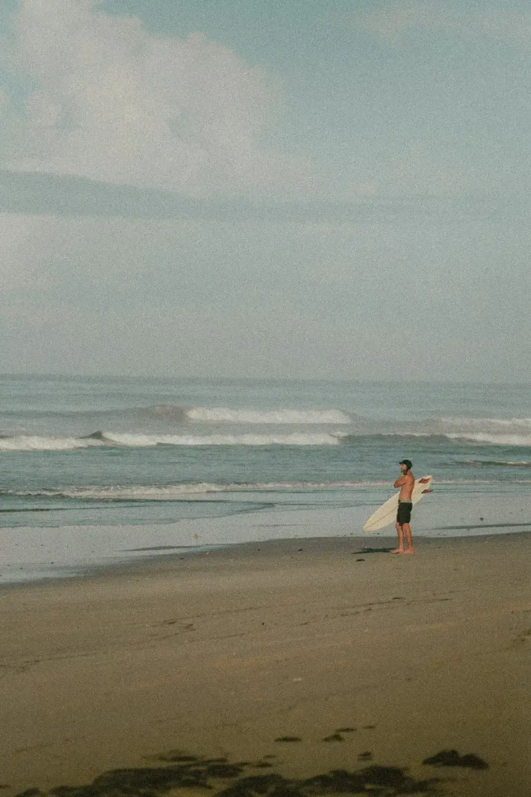 A man stading with Surfboard