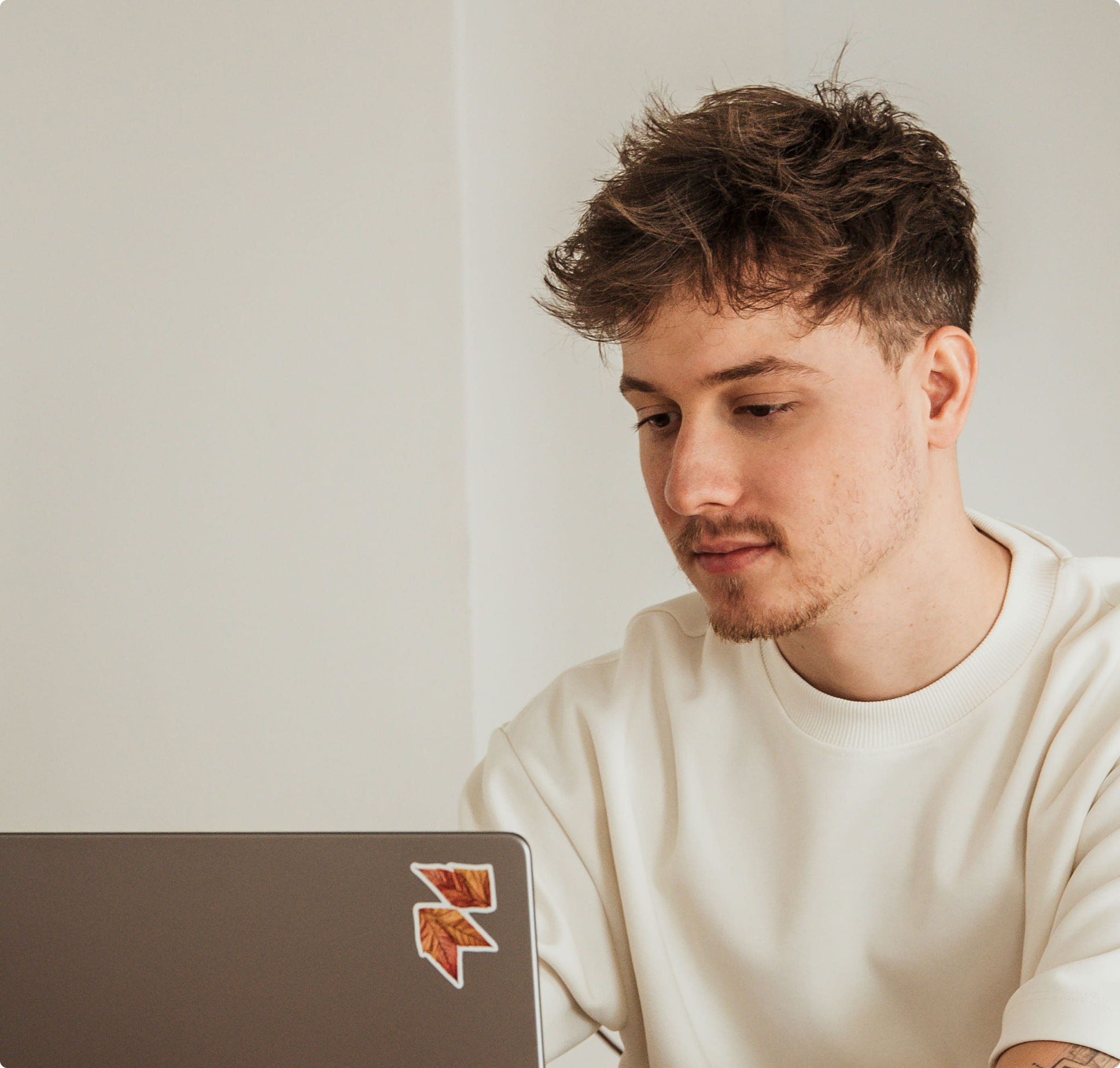 Young man working on laptop, focused expression. Indoor workspace.
