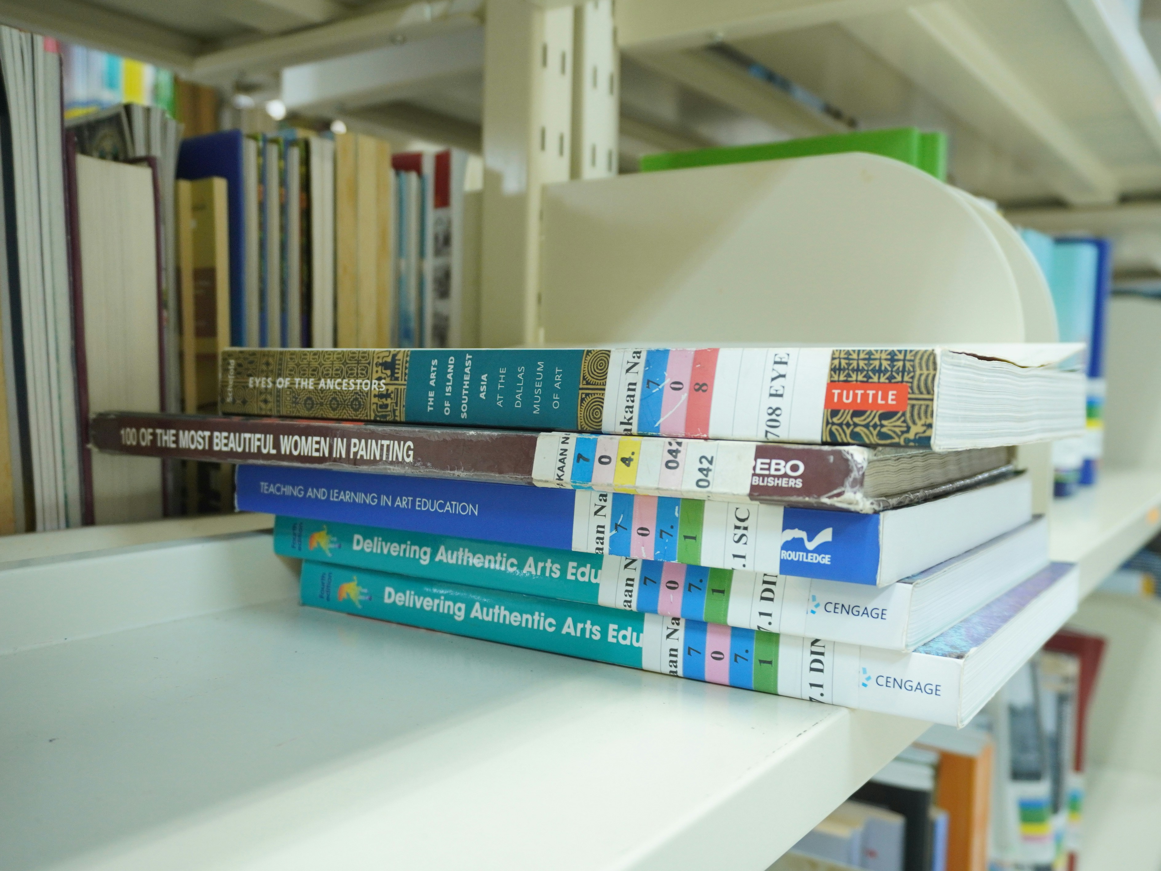A stack of books sitting on top of a white shelf