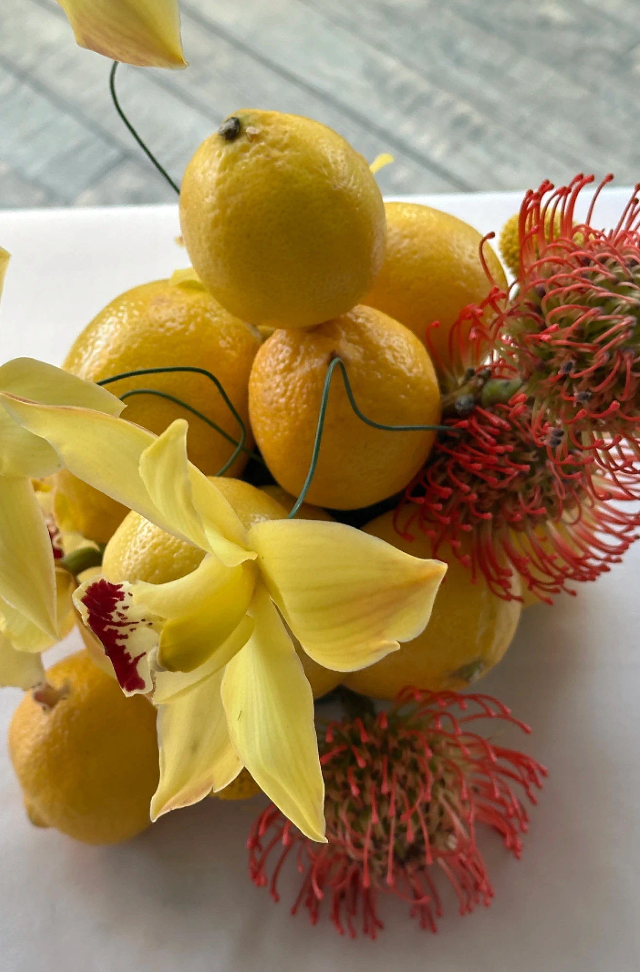 Detalle de mimosa amarilla, narcisos y hierba ornamental verde en un diseño floral silvestre para centros de mesa.