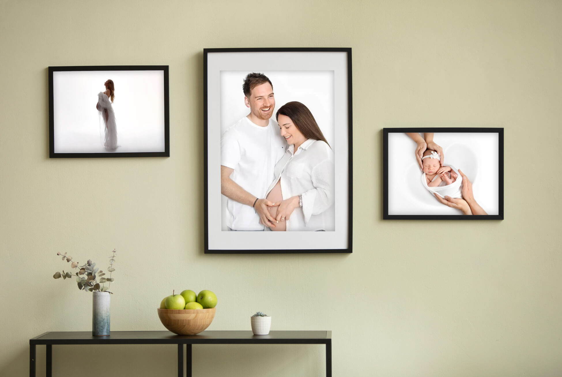 Wall display featuring framed images from a maternity photoshoot, showcasing a couple’s joyful and intimate moments together.