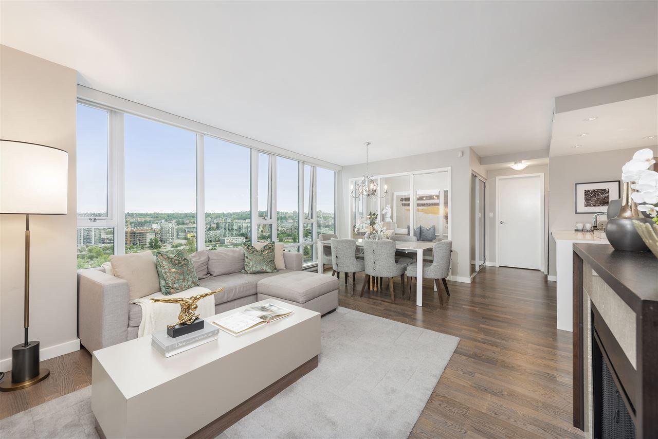 Modern living room with large windows, stylish furniture, and a view of greenery outside. Bright and airy atmosphere.