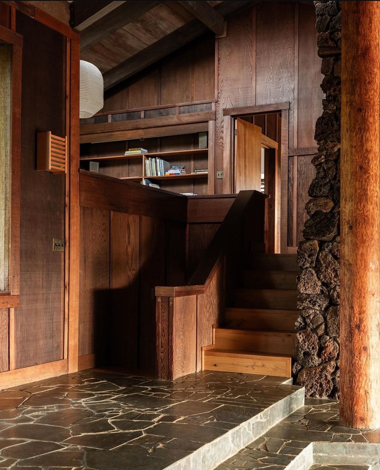 Calm entry hall with symmetrical cabinets, a sculptural plant, artwork, and a round table.