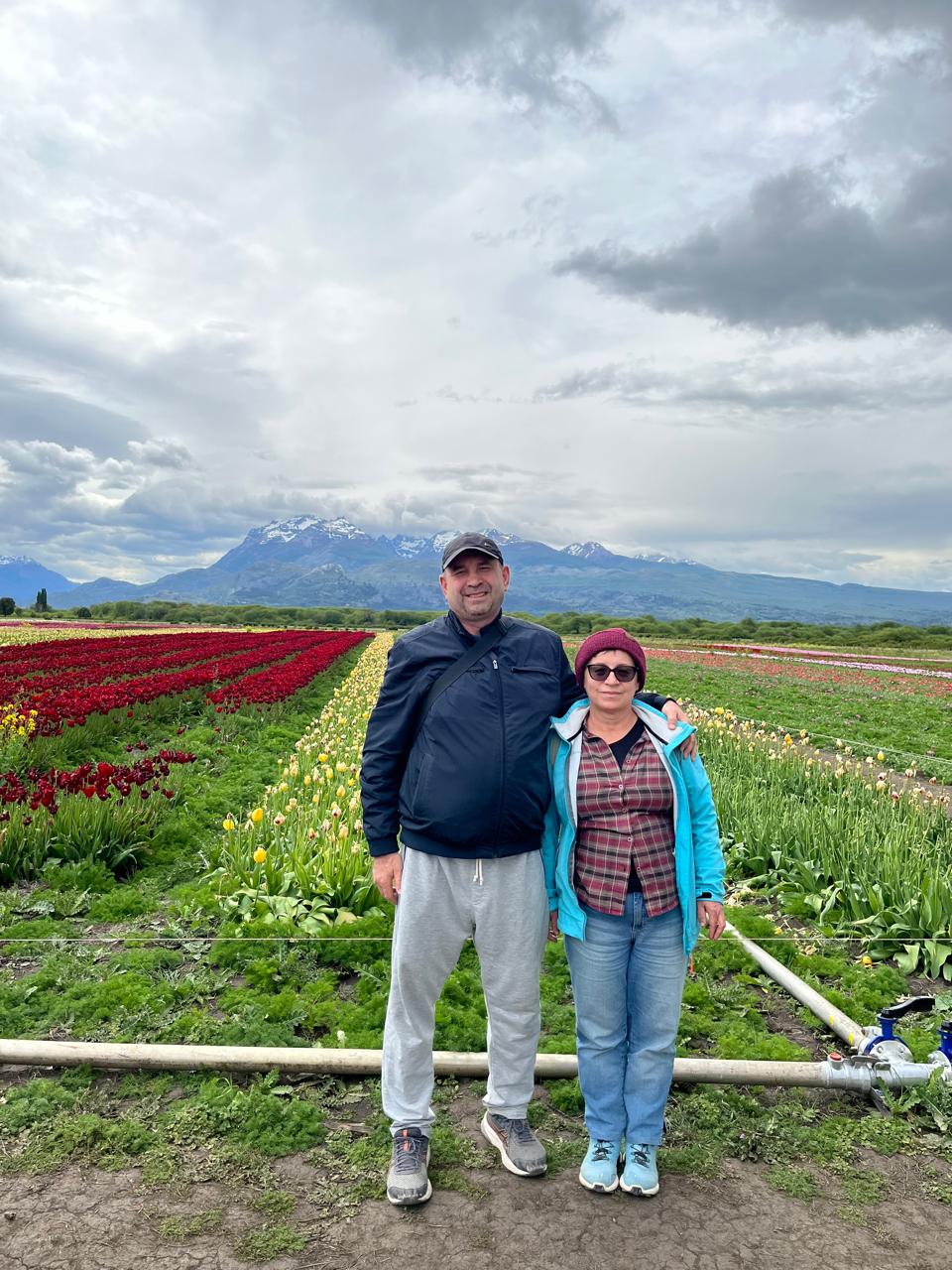 Mujer sentada sobre un tronco frente a una cascada doble en un bosque frondoso de Argentina.