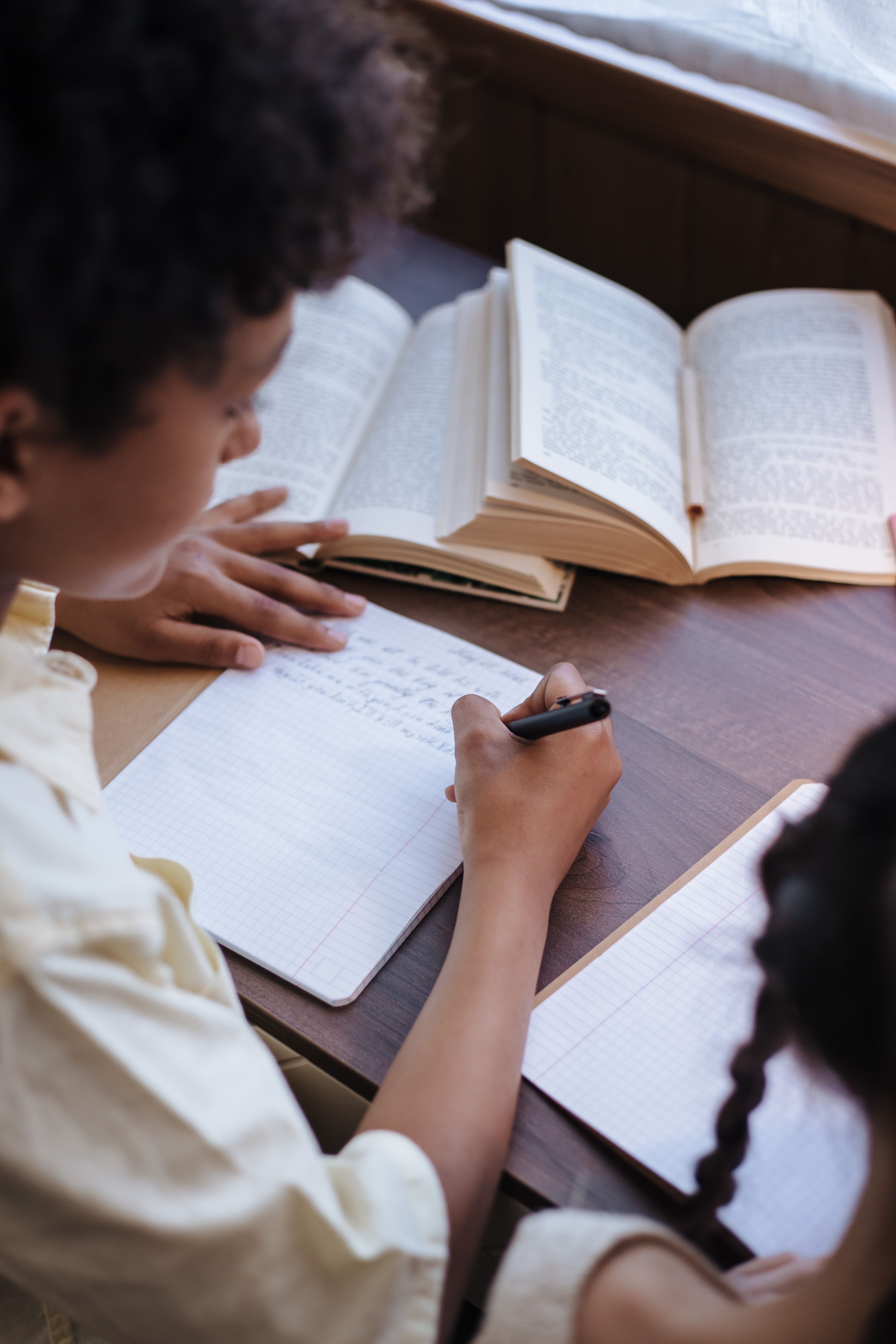 Young Black students writing in notebooks in a classroom
