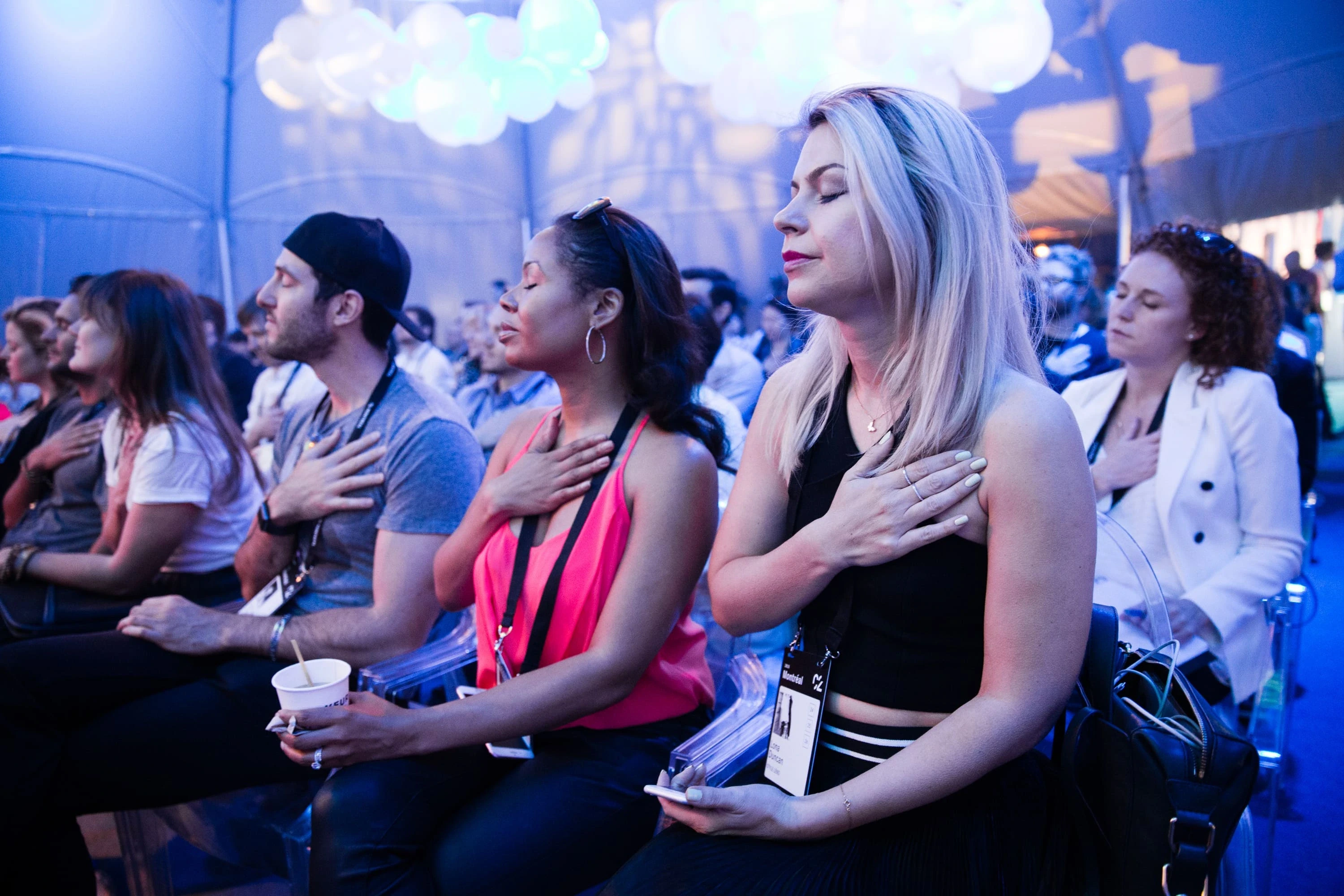 C2 attendees participating in a reflective moment during a conference session, hand on heart.