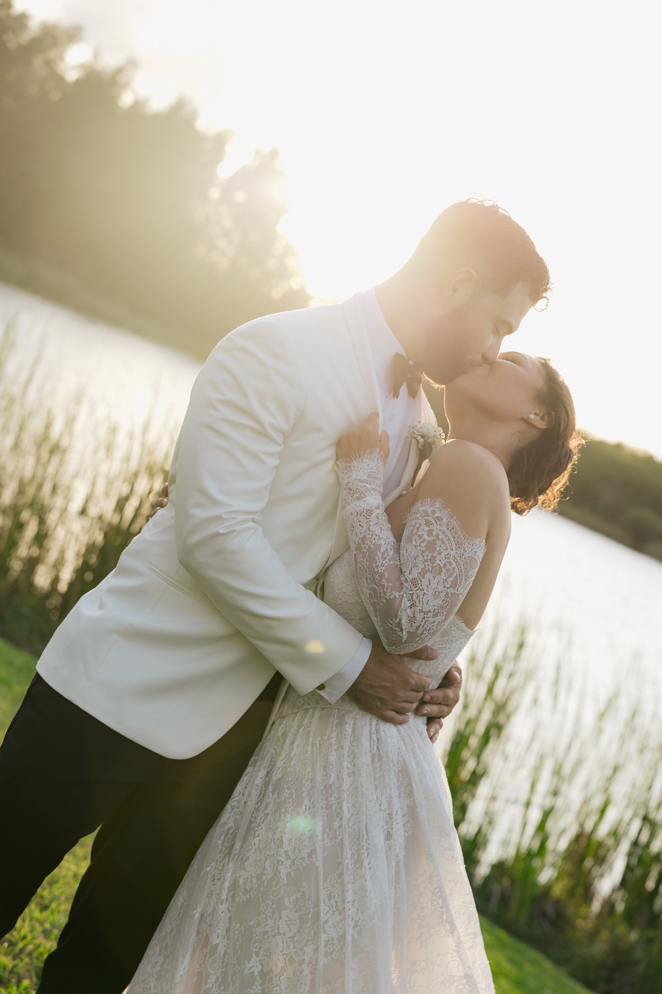     Palm Beach wedding photographer captures a couple embracing in golden light during a lakeside wedding portrait.