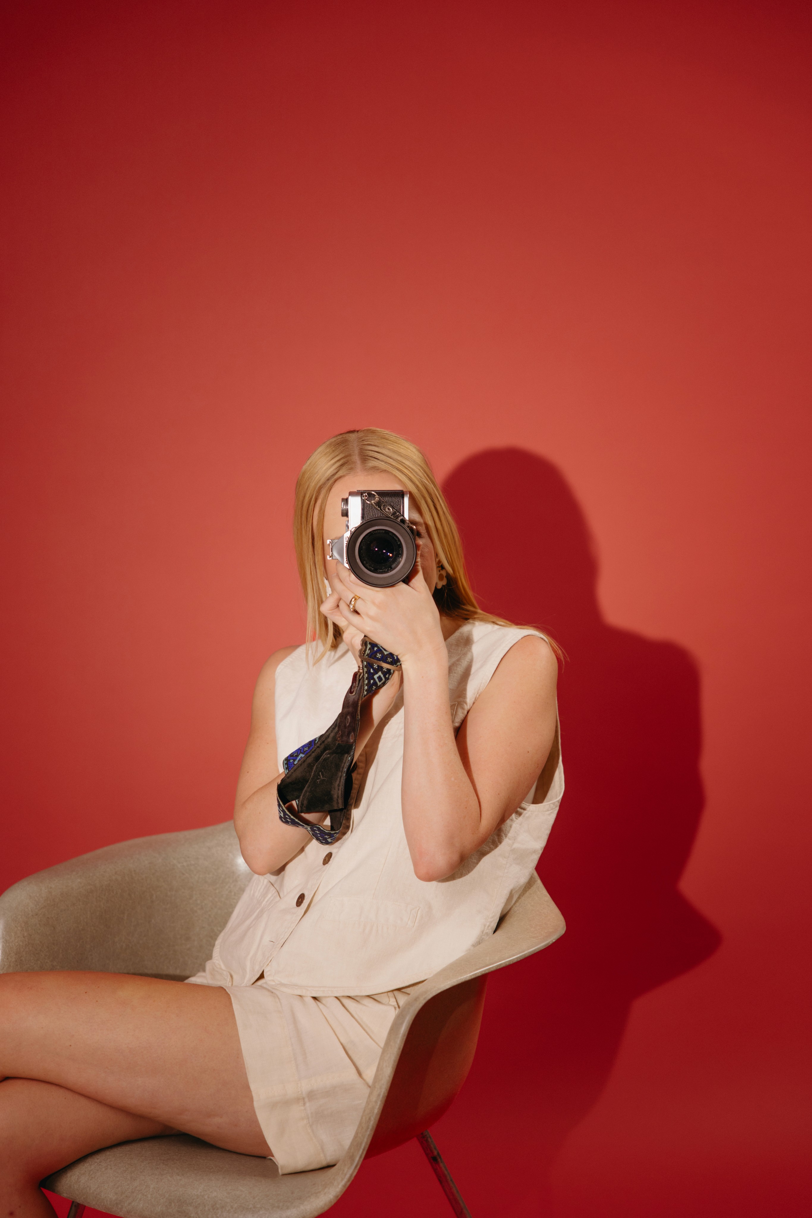 Elise on a red backdrop taking a picture of the viewer