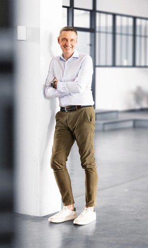 Business Coach Stefan Bischo von Leadtransform steht entspannt im modernen Büro