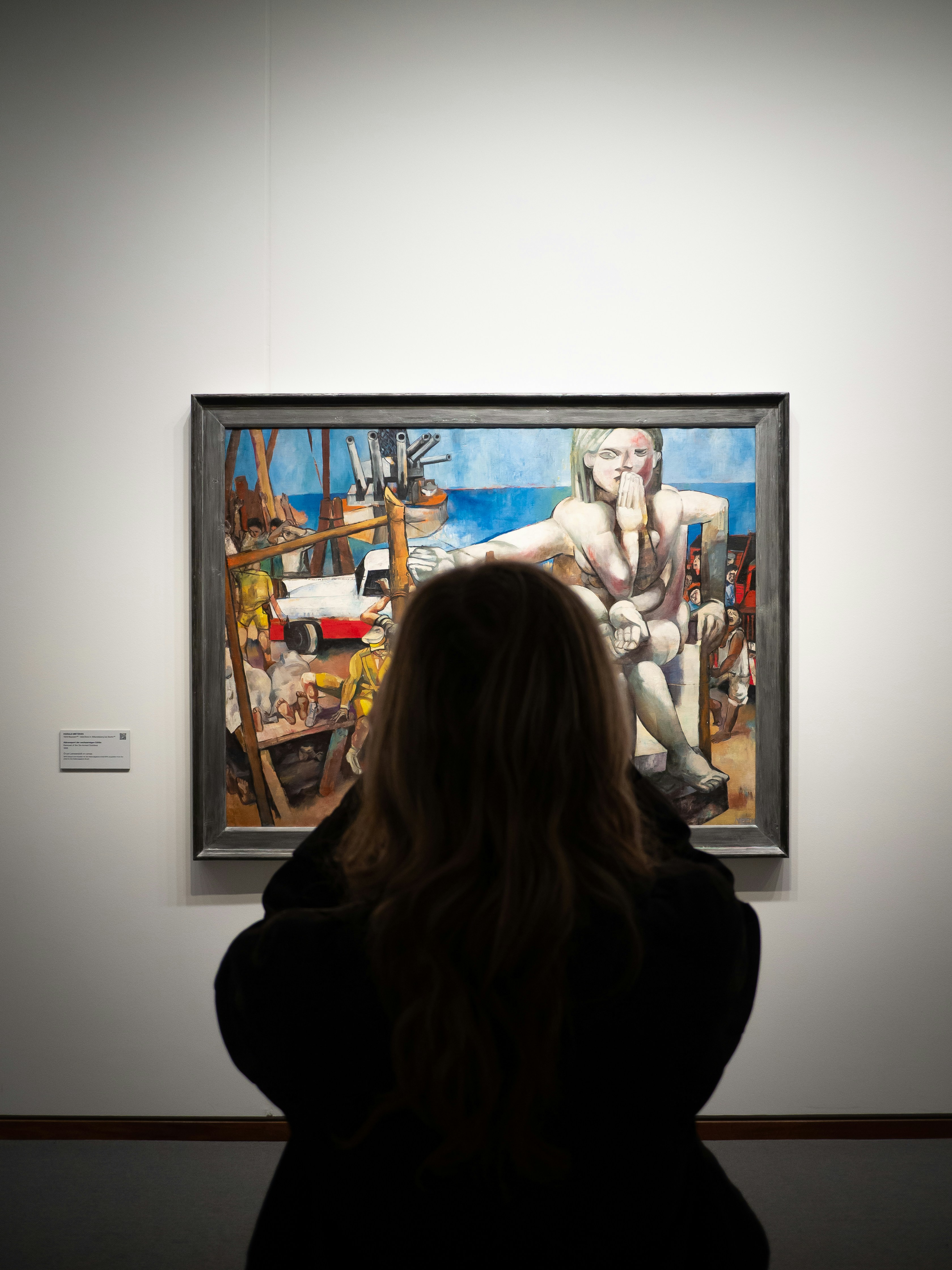 Person admiring a painting in an art gallery.