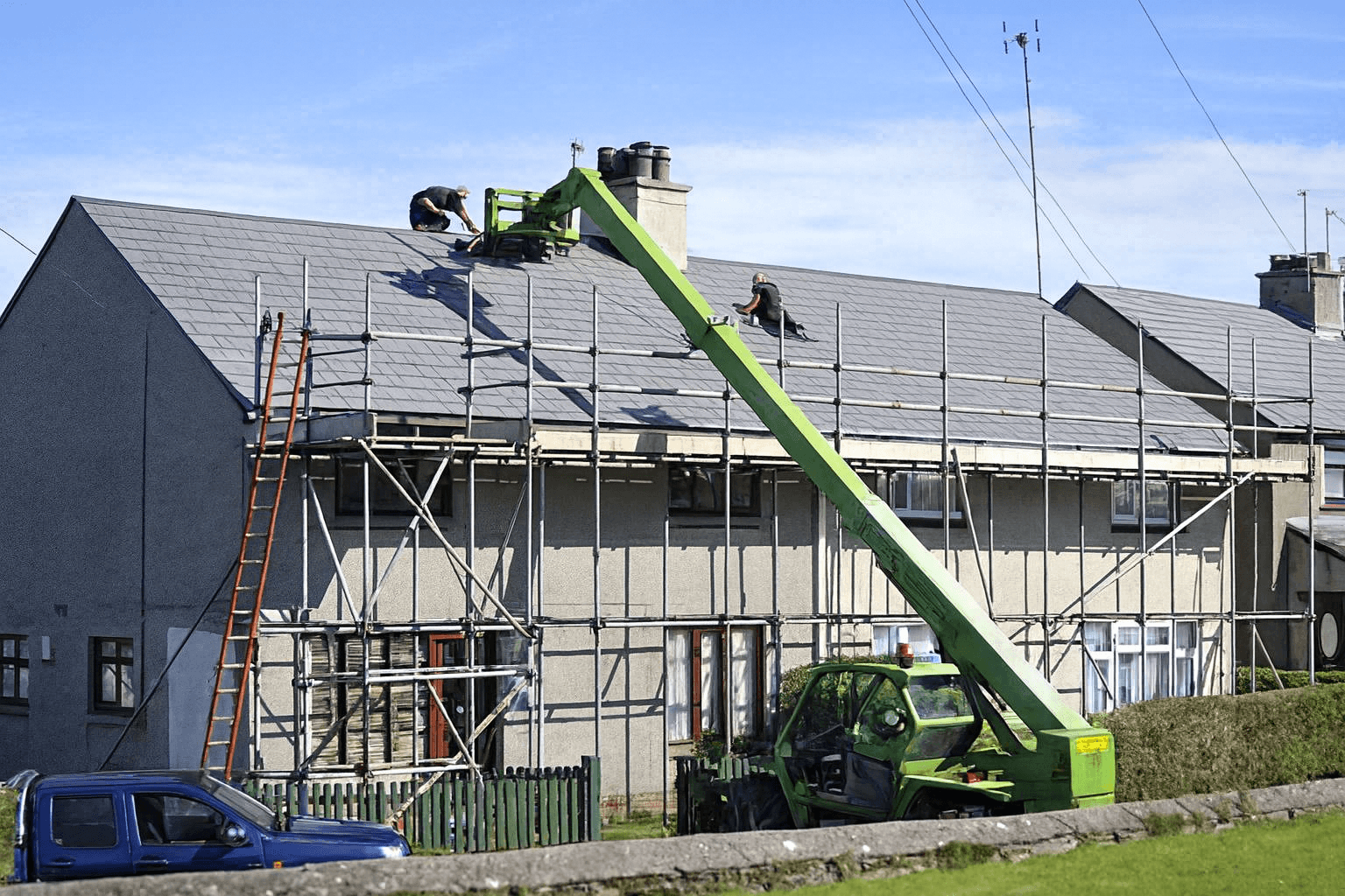 Large two-story barndominium with gray metal siding and roof, wraparound porch, and warm glowing windows at sunset, set on a spacious green lawn.