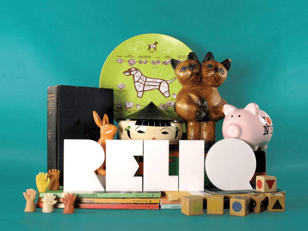 A screenshot of the Reliq website displays a navigation bar with options like "Appraisal," "Important Artifacts," "Interviews," and "Browse Objects." Prominently featured are three toy dogs on a pink surface, highlighting the site's focus on personal objects and their stories.