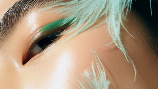 Close-up of an eye with creative makeup and white feathers.