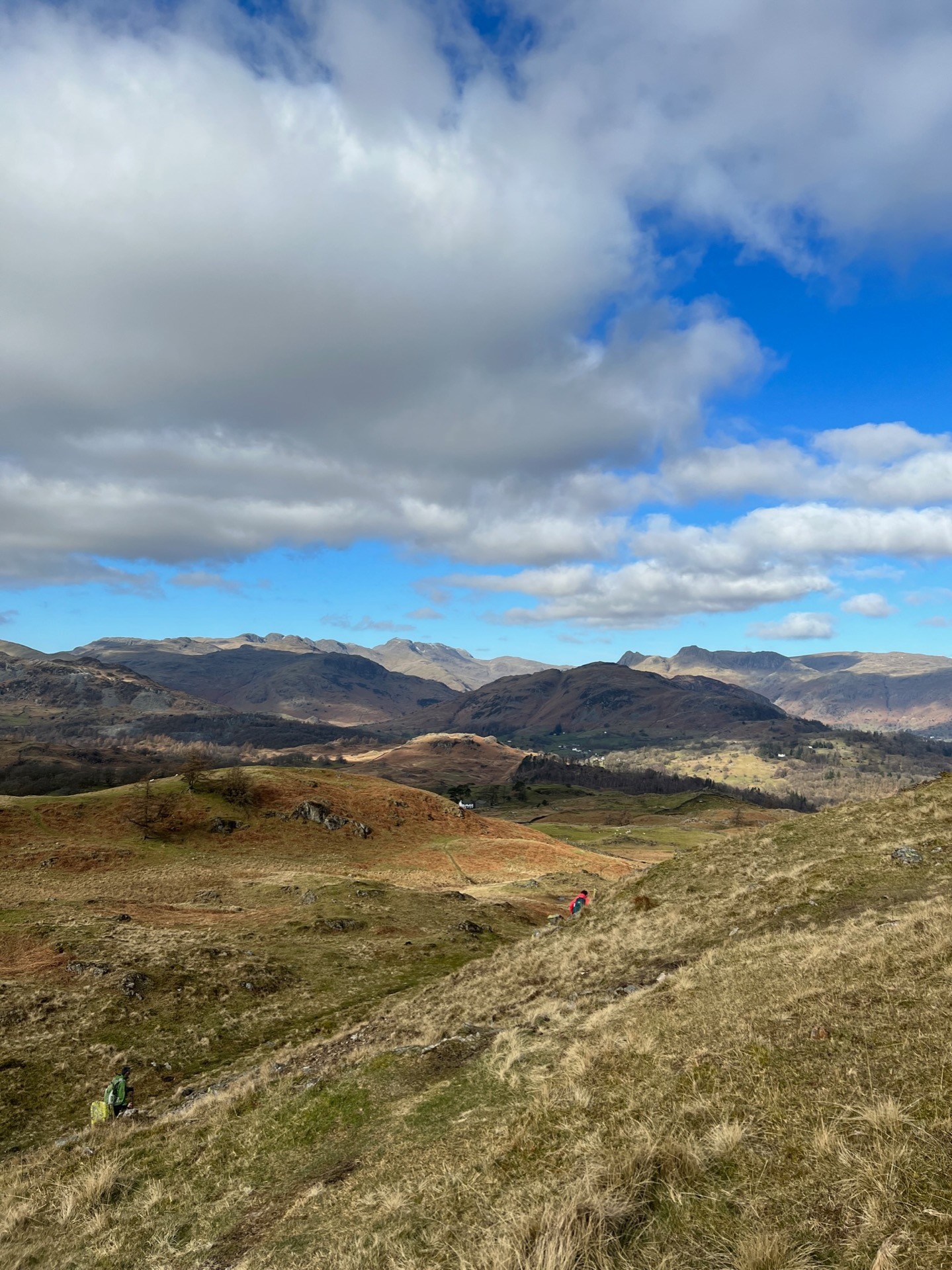 The views seen from Black Fell. A wide open mountain range with blue skies and open fields.