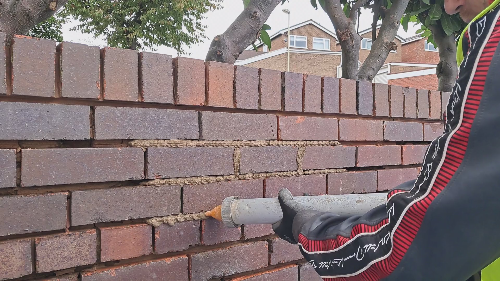 A man filling joints on a wall with a pointing gun