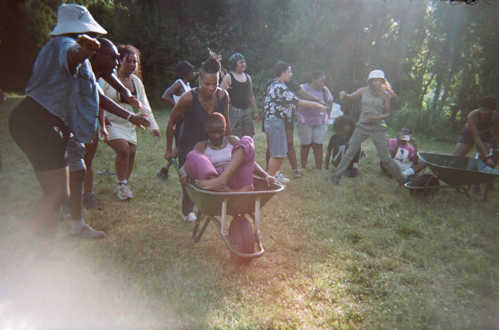 Someone sits in a wheelbarrow while another person pushes it in a race