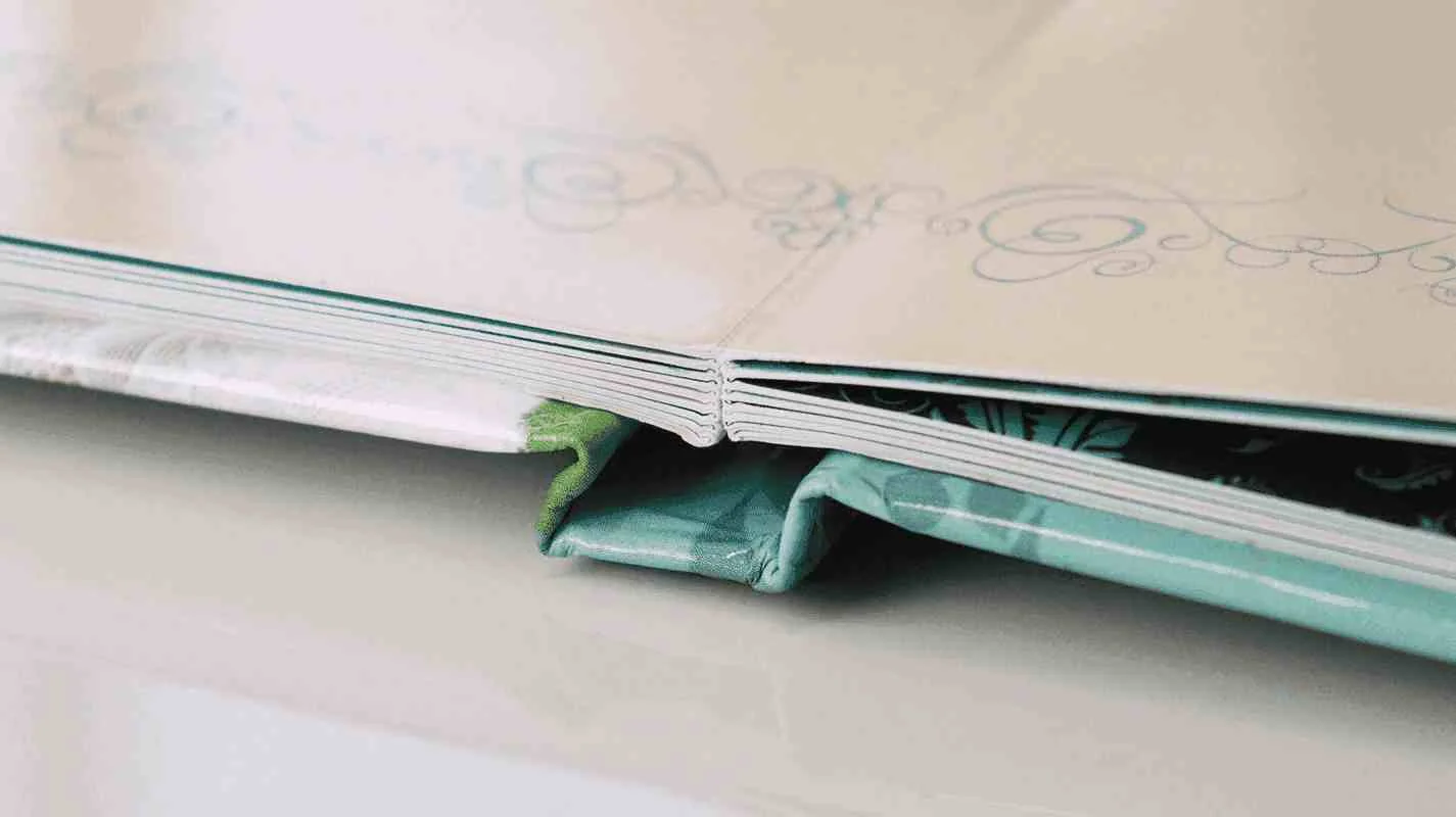 Detalhe do acabamento de um fotolivro aberto em 180 graus, mostrando a encadernação lay-flat que permite páginas totalmente planas.