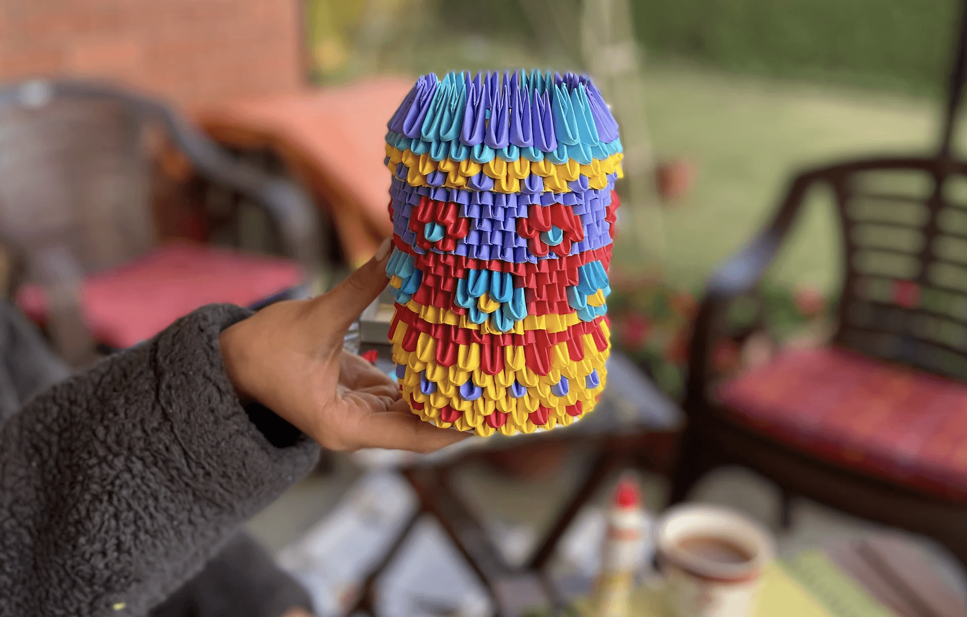 A person stands outdoors in a natural setting with lush green trees under a clear sky, wearing a dark sweatshirt, and looking into the distance.