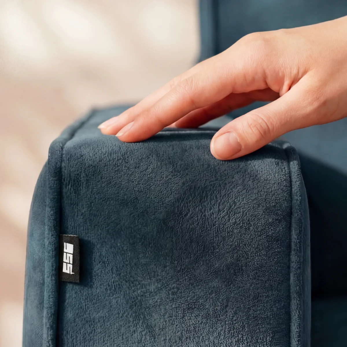 Detailaufnahme eines blauen Samtsofas mit dem gewebten Marken-Label der Sunken Sofa Company zur Darstellung der haptischen Materialqualität.