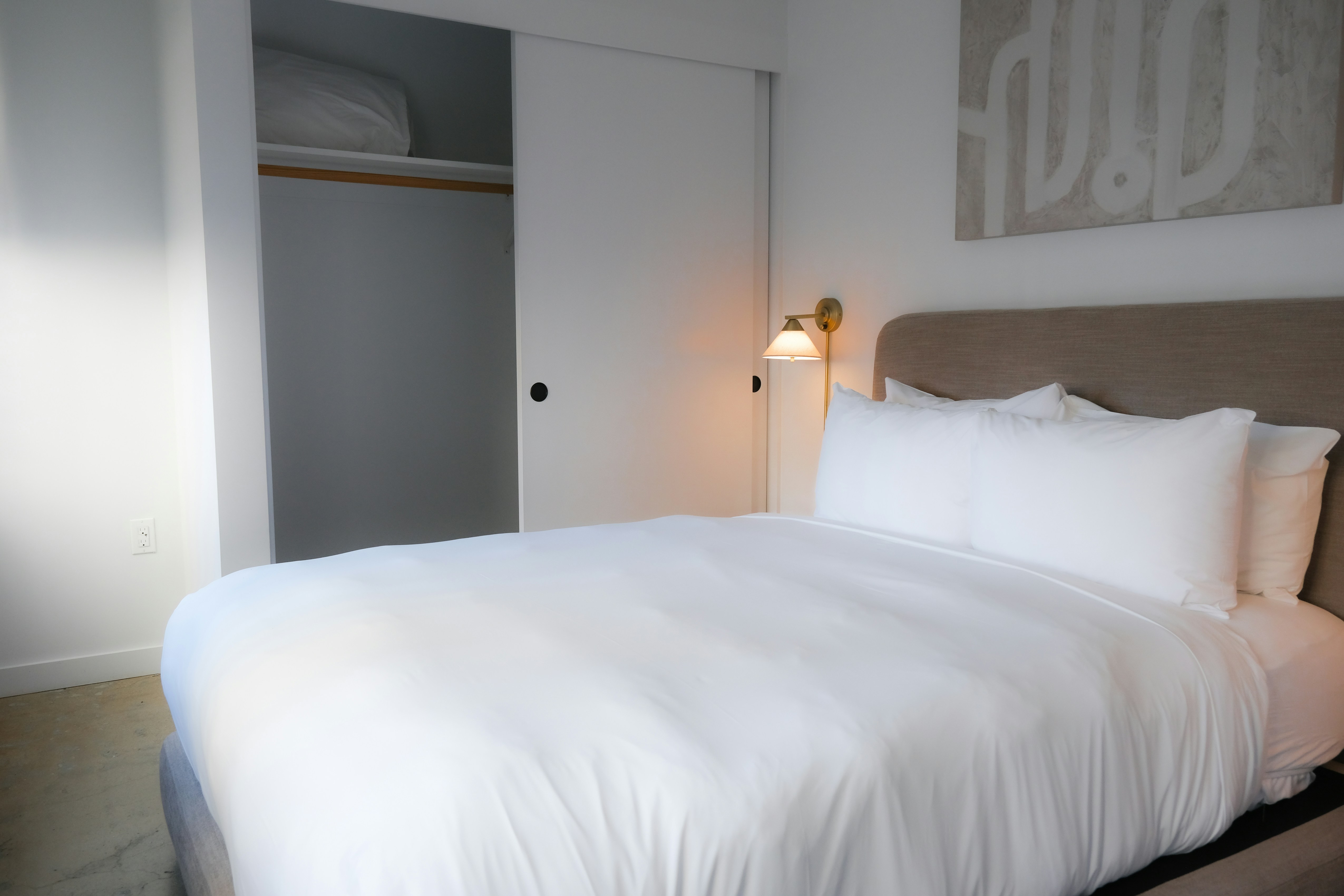 A neatly made bed with white linens in a bedroom.