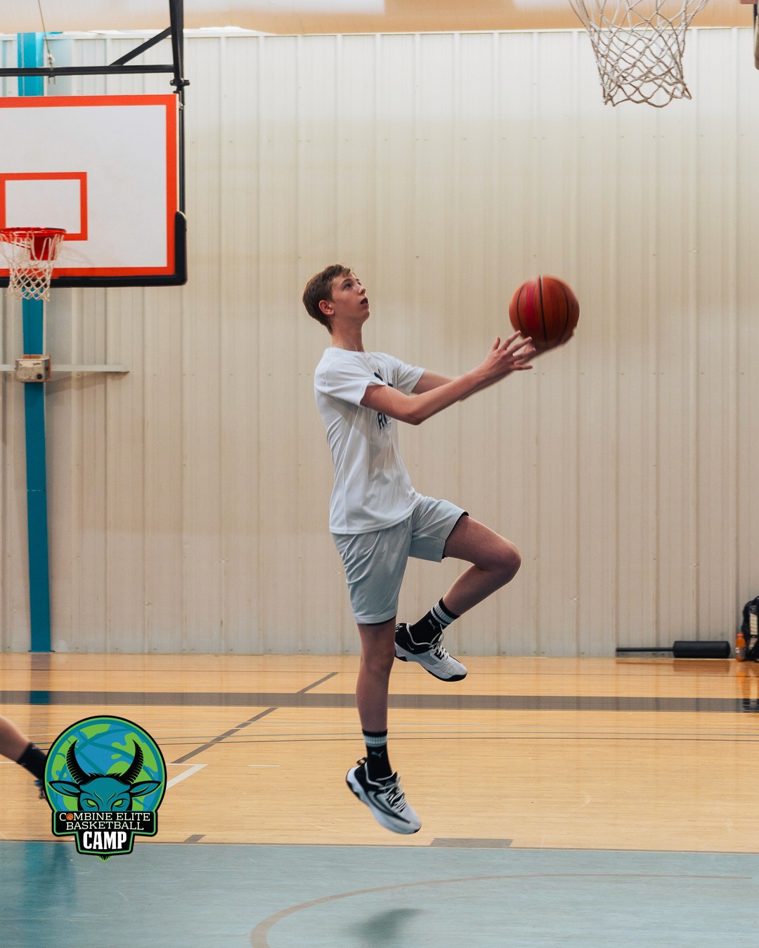 Jeune joueur de basket en train de tirer au panier lors d’un camp d’entraînement.