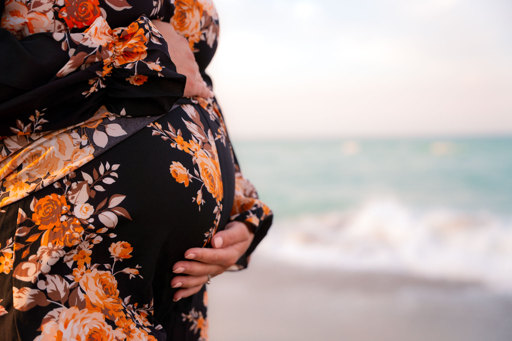  a woman's belly with the floral dress in front of an ocean scene