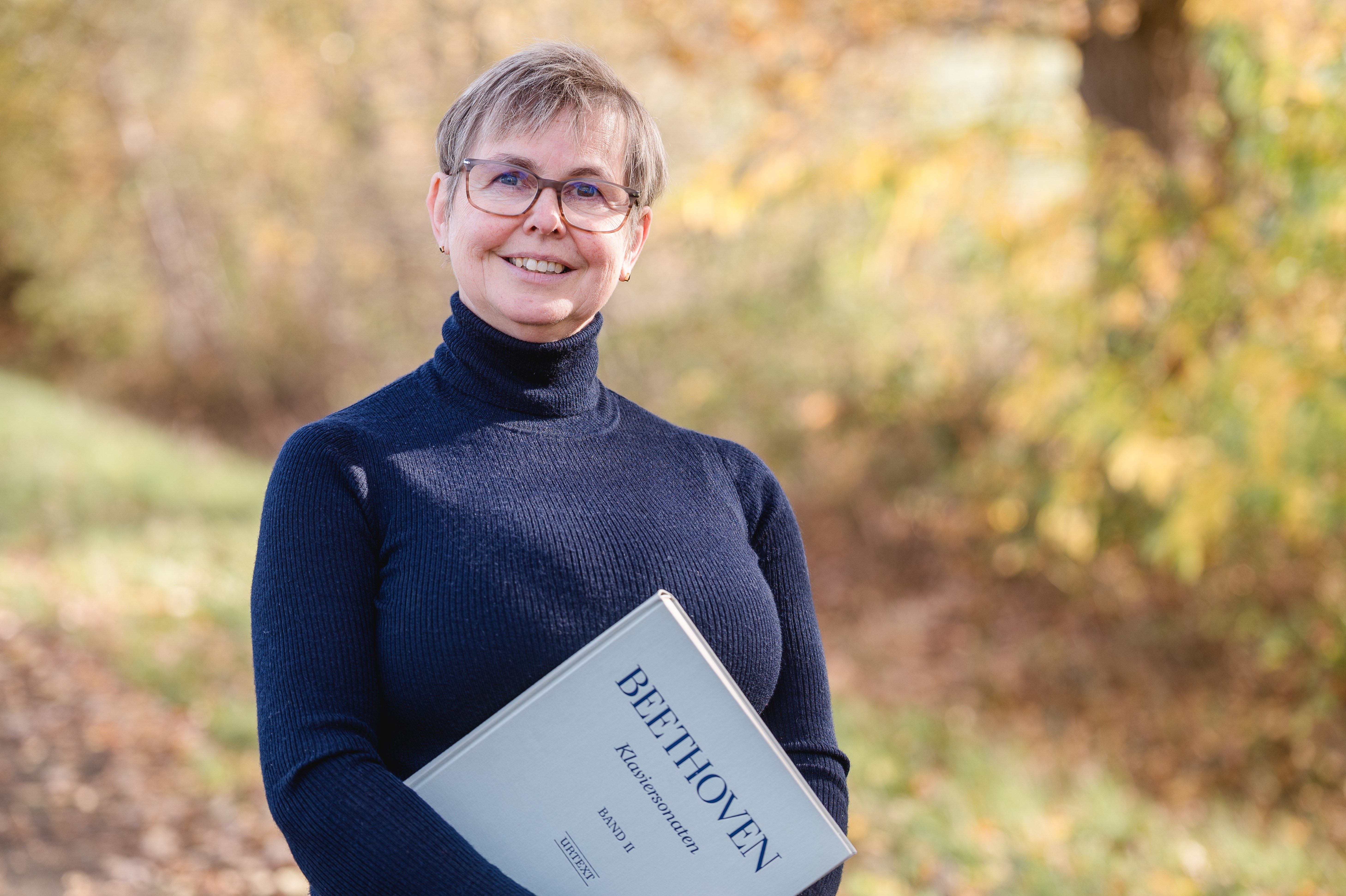 Portrait einer Frau mit Brille und Klavierband in den Händen