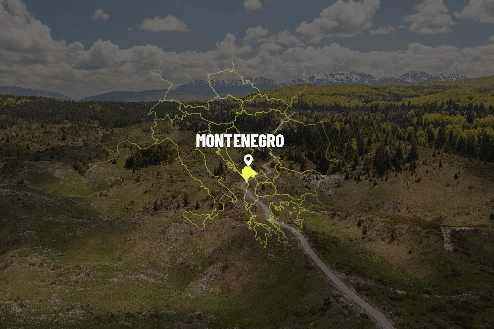 Beautiful serpentine road through the Durmitor National Park in Montenegro, surrounded by green forests, alpine meadows, and snow-capped mountain peaks in the background.