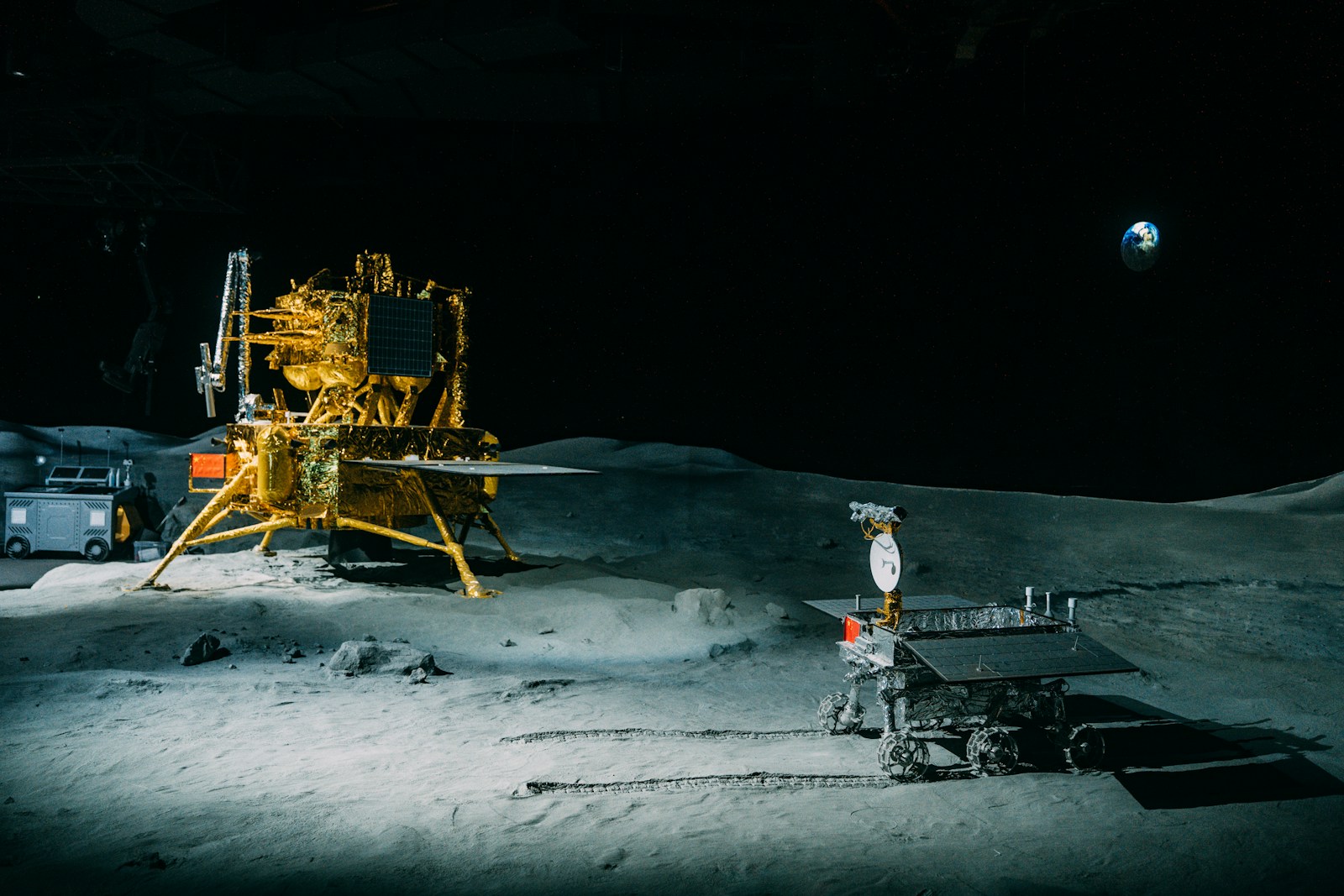 A lunar lander and rover on the Moon's surface with Earth rising in the distance