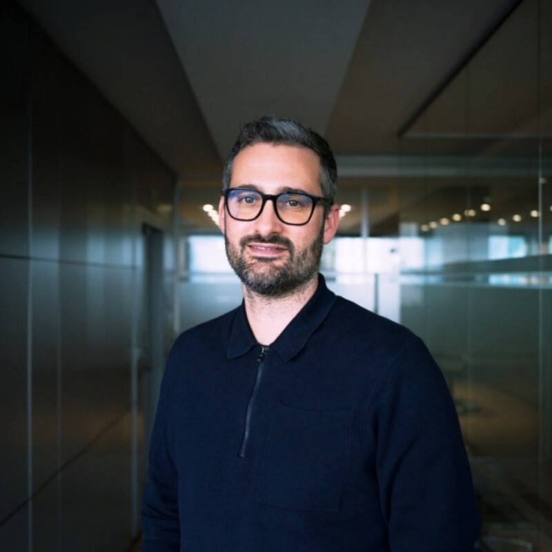 Fred the CEO of outra, wearing glasses, and a dark navy long sleeve zip up polo