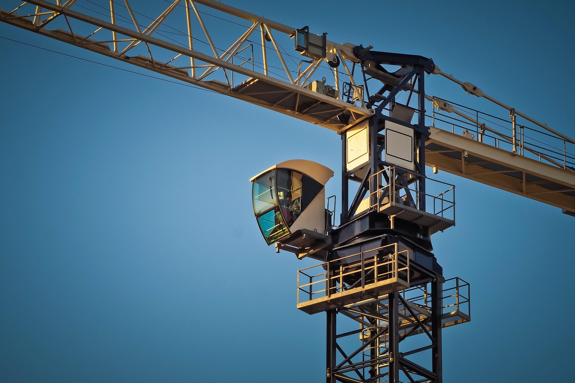 Grua de construção civil com cabine de operação, representando obras, engenharia, infraestrutura e desenvolvimento imobiliário.