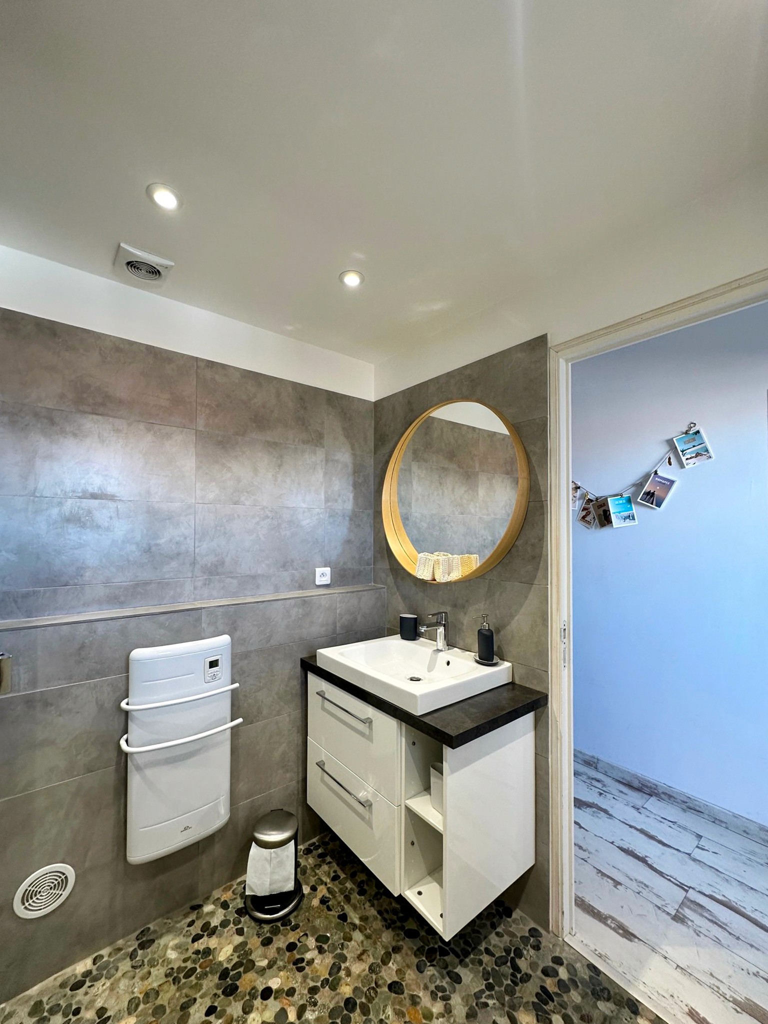 Aménagement salle de bain zen avec douche à l'italienne en travertin, meuble en bois clair et décoration bohème.