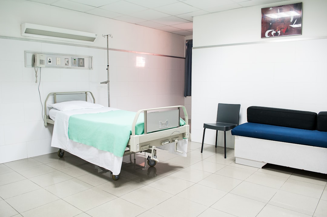 healthcare professional in medical scrubs using a digital tablet in a hospital corridor, soft blue lighting, professional clinical environment