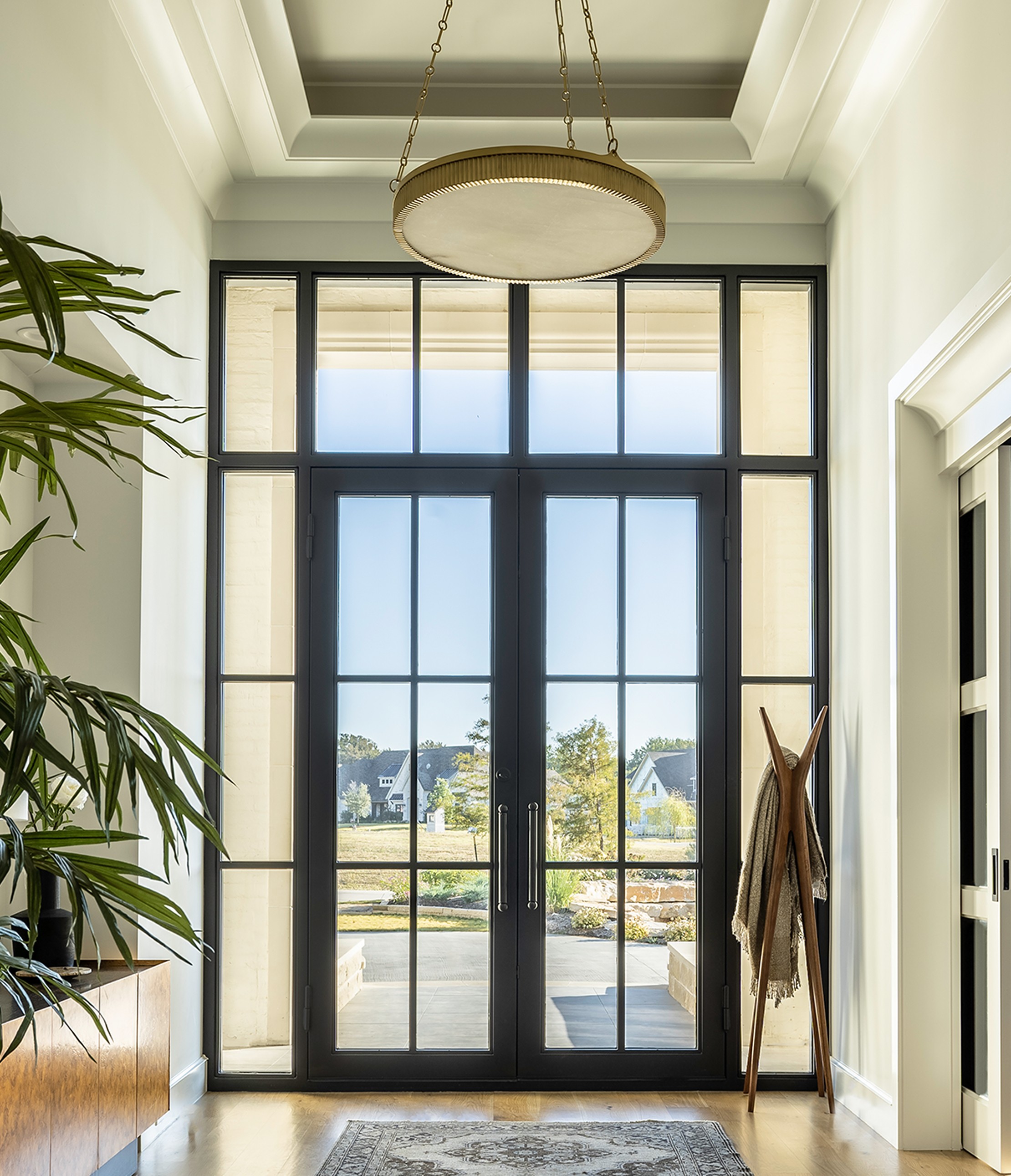 Fairview primary suite bedroom with dark walls, modern chandelier, tufted headboard, and seating area by large windows