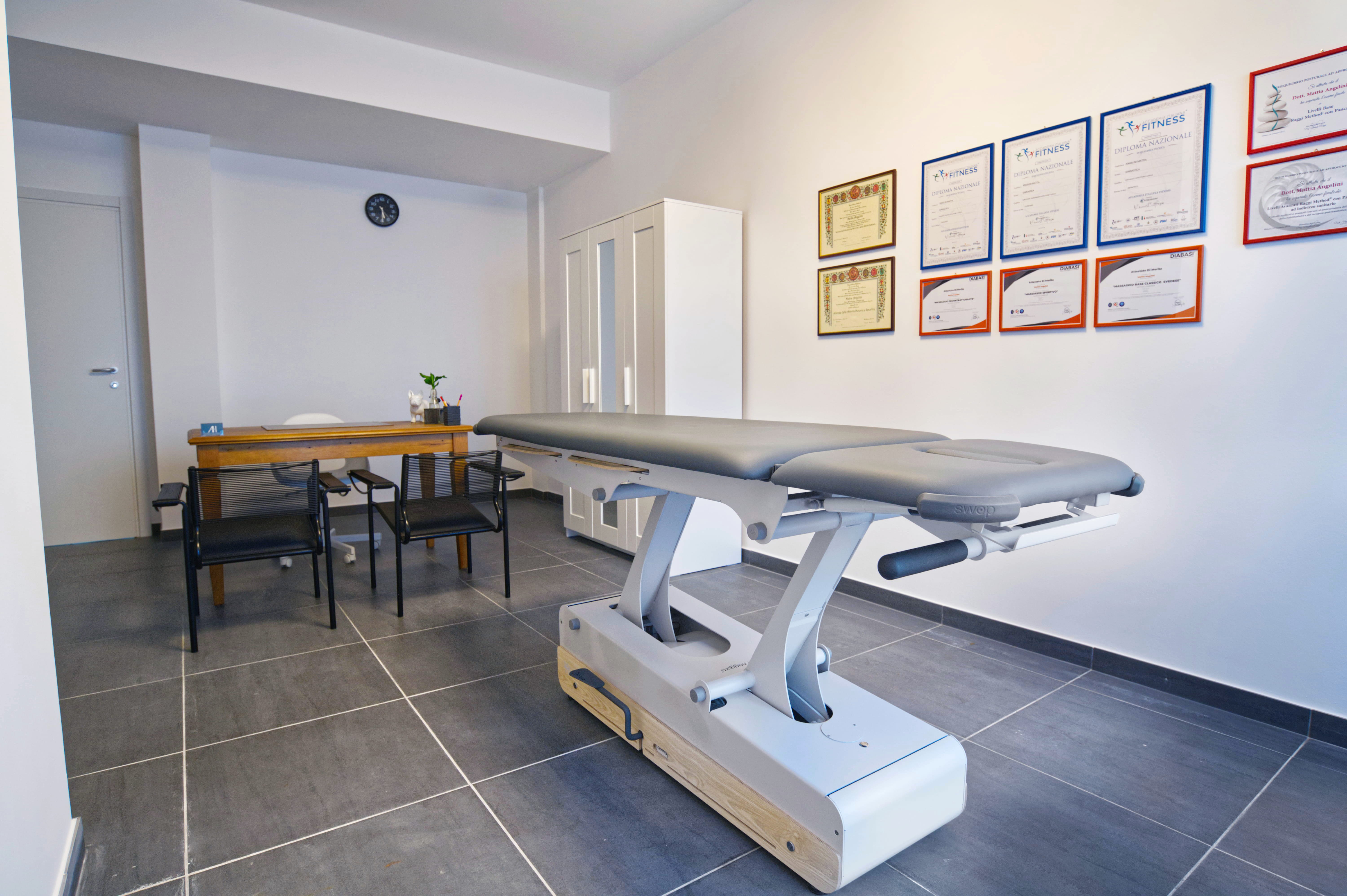 A man and woman sit on beige chairs in a modern room with a red paneled wall. A red pendant light hangs above a wooden coffee table between them.