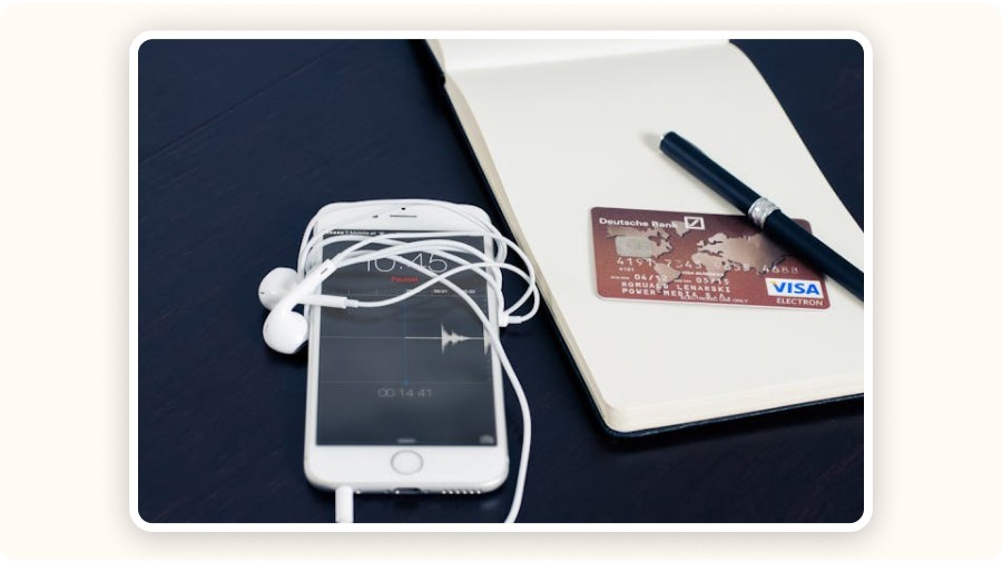Visa card next to a smartphone and earphones