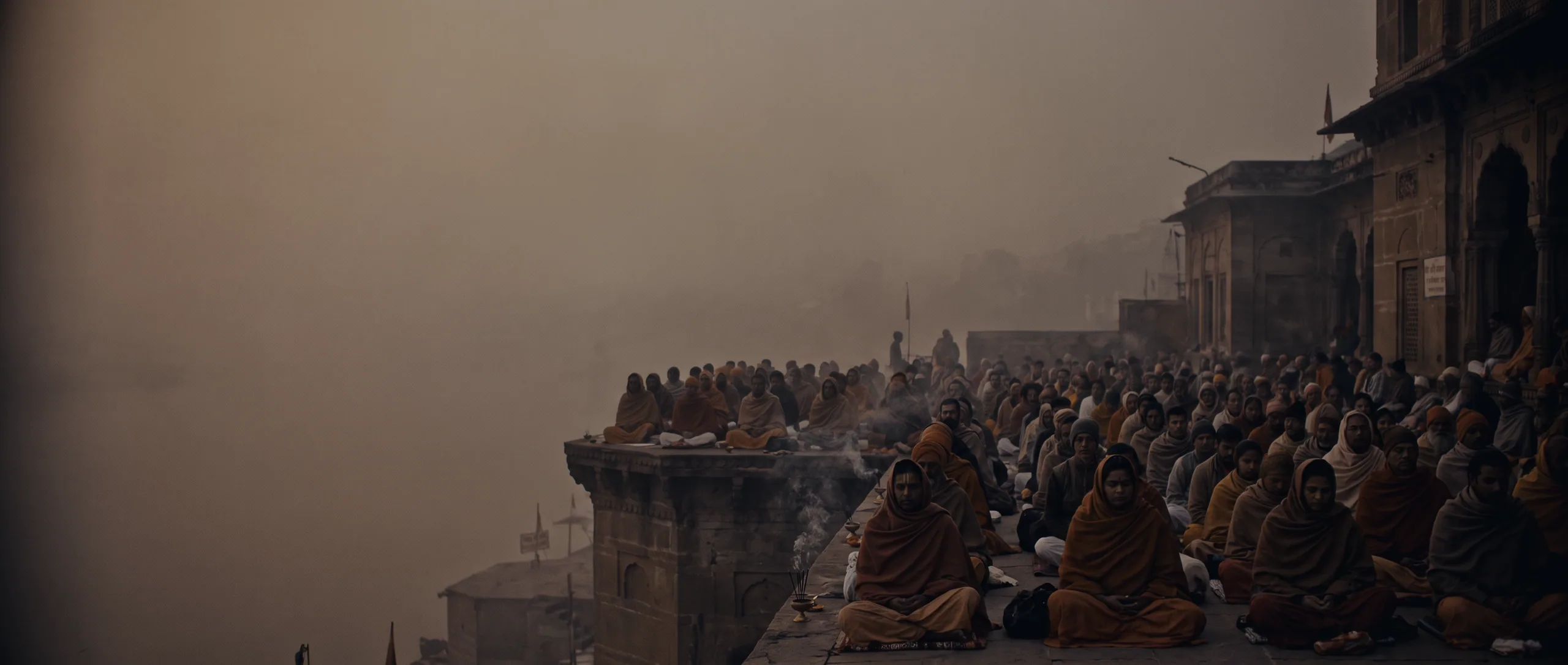 Concept art: hundreds of figures seated in rows on riverfront steps in cold smoke at first light, temple architecture behind them.