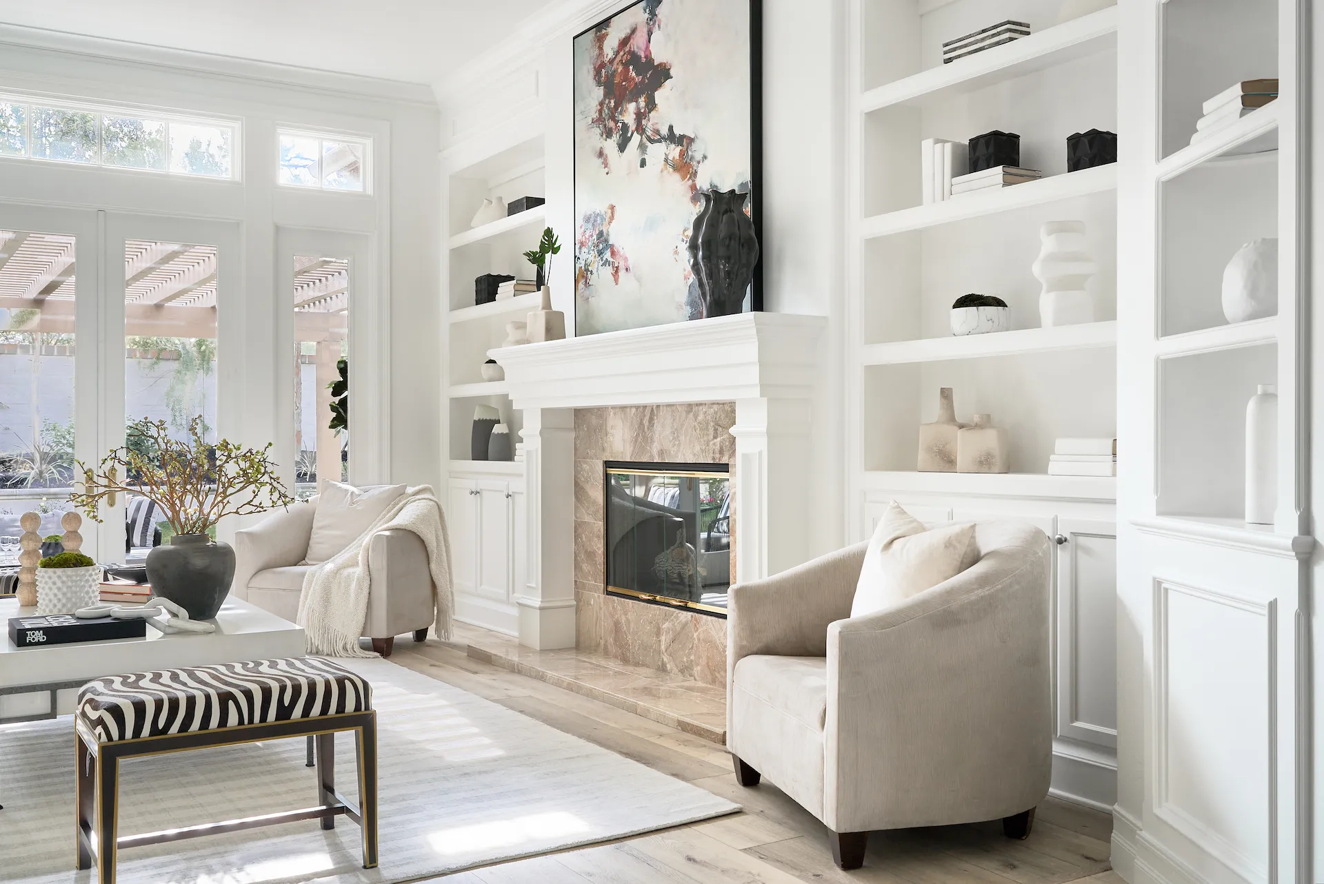 View of the living room's fireplace wall, adorned with elegant decor and a marble-clad fireplace, adding a touch of luxury to this Tustin Ranch home. Photo by Todd Huge.