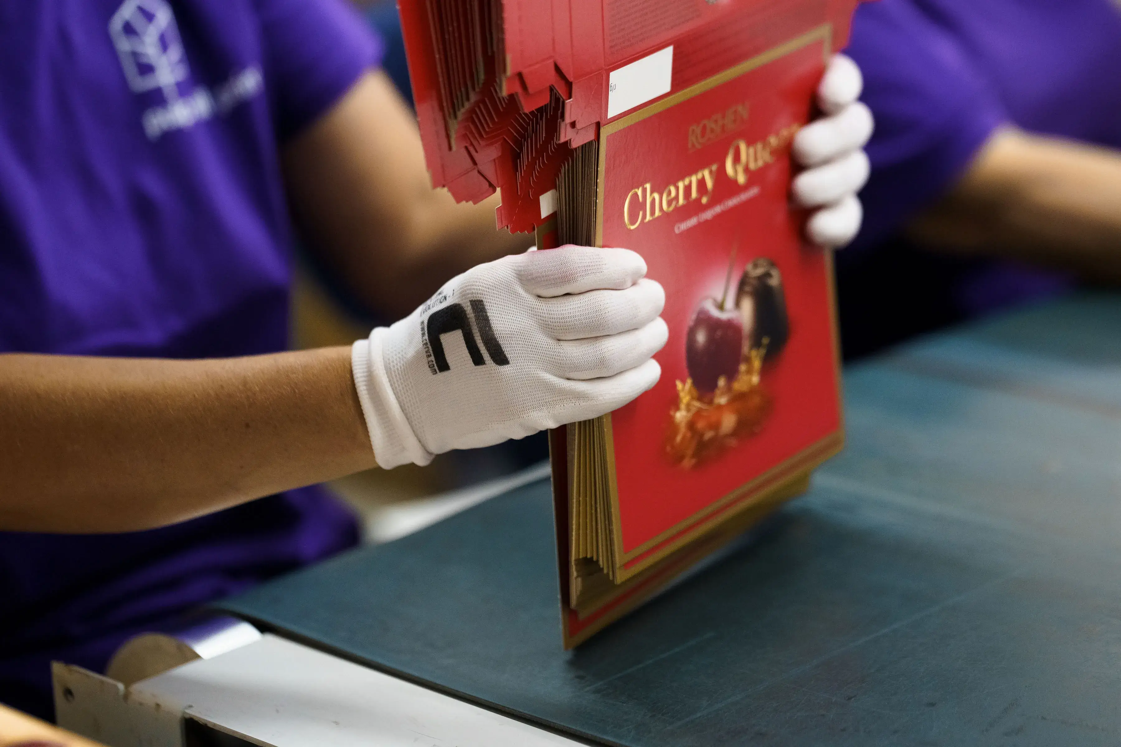 Робітник у рукавичках тримає книгу у фабриці.