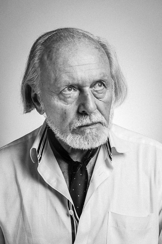 Portret starszego mężczyzny z siwą brodą, ubranego w koszulę i fular.