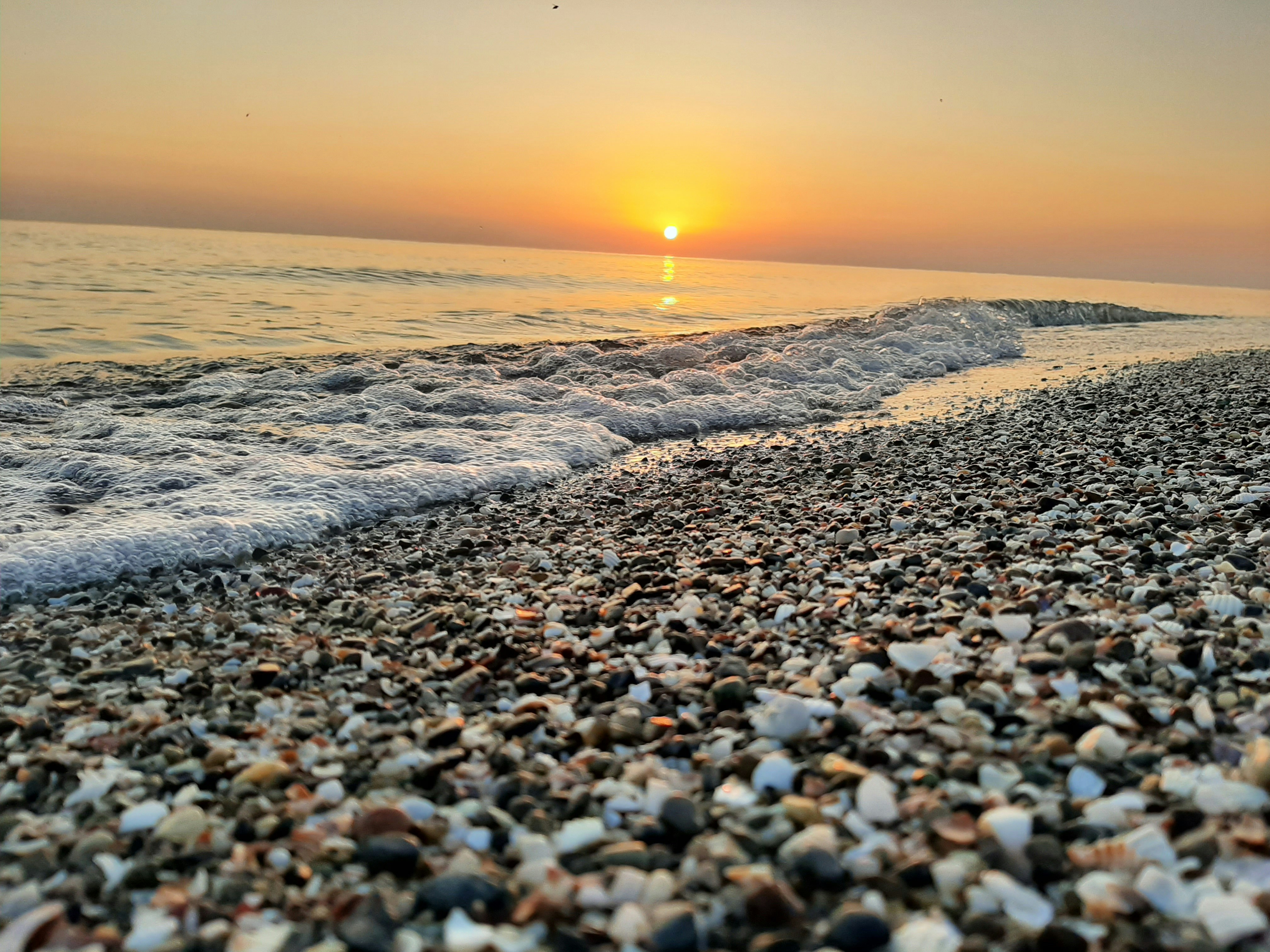 the sun is setting over the ocean on the beach
