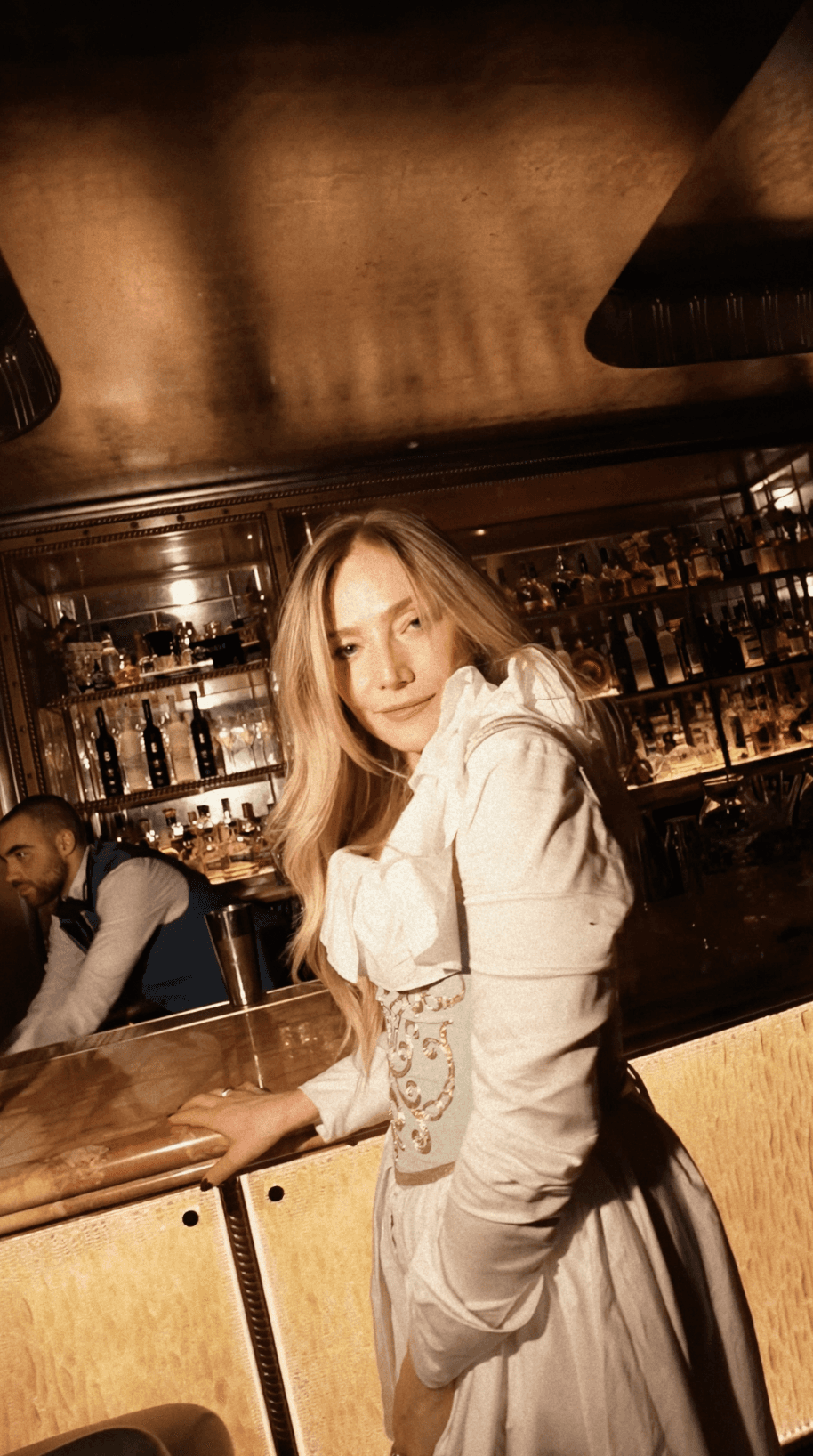 Bride sitting on ground against wall, groom standing nearby