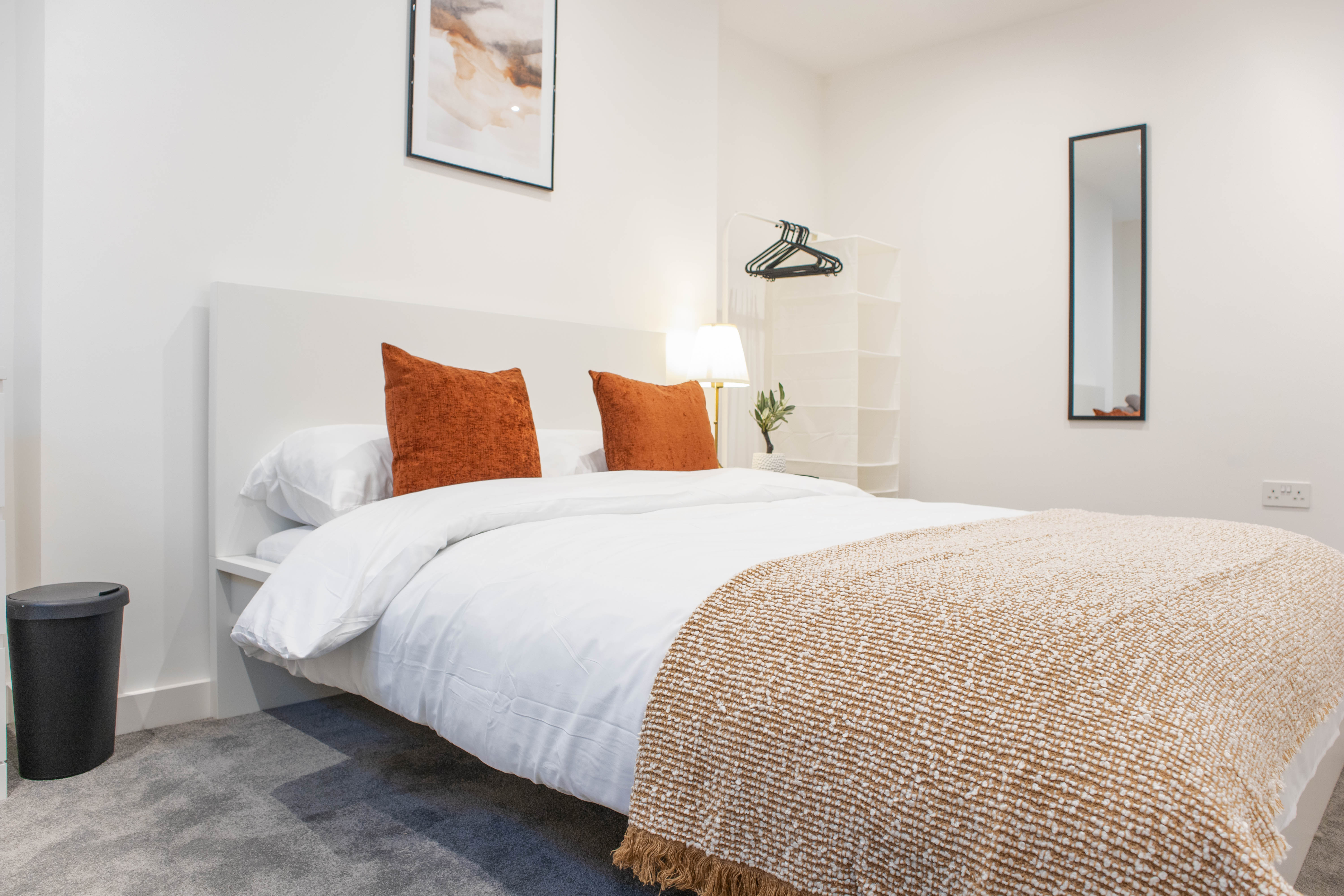 Bright modern Airbnb bedroom with double bed and orange cushions