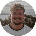 Tyler, 34, smiling outdoors in coastal sunset portrait for customer testimonial