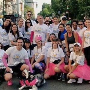 Group of diverse runners in matching outfits at charity race event outdoors.