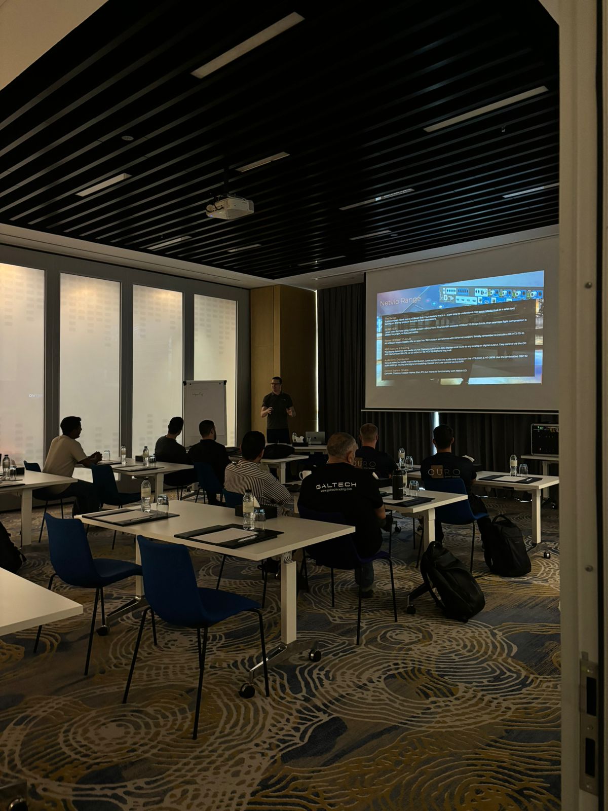 Presentation in a modern conference room with projector and attendees.