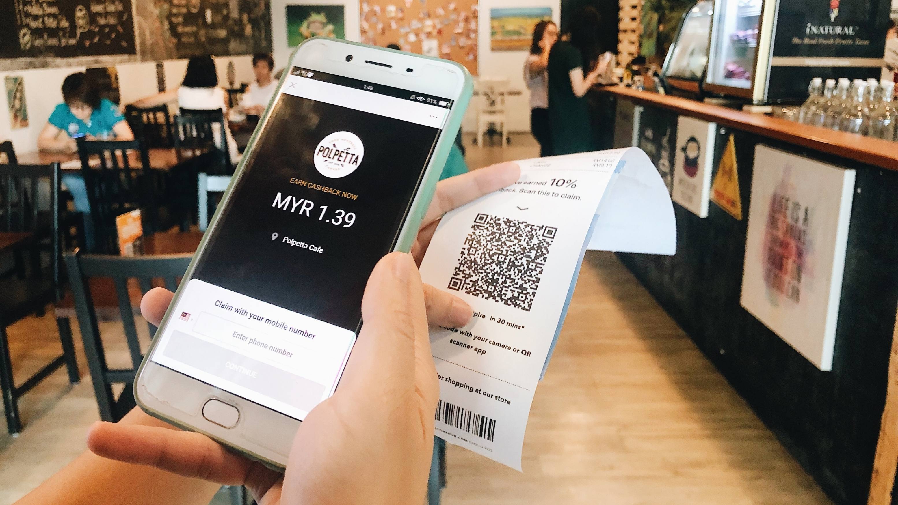 一名顾客在咖啡厅使用手机扫描收据，以领取返现 
