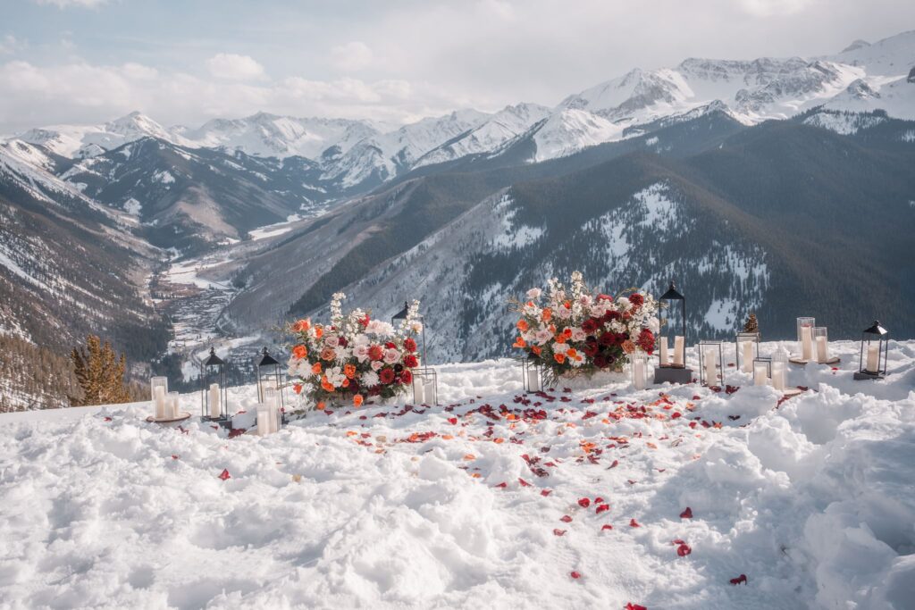Proposal setup at Smith Cabin Aspen showing floral arrangements, lanterns, and rose petals in snow above the Roaring Fork Valley, set before the couple arrived