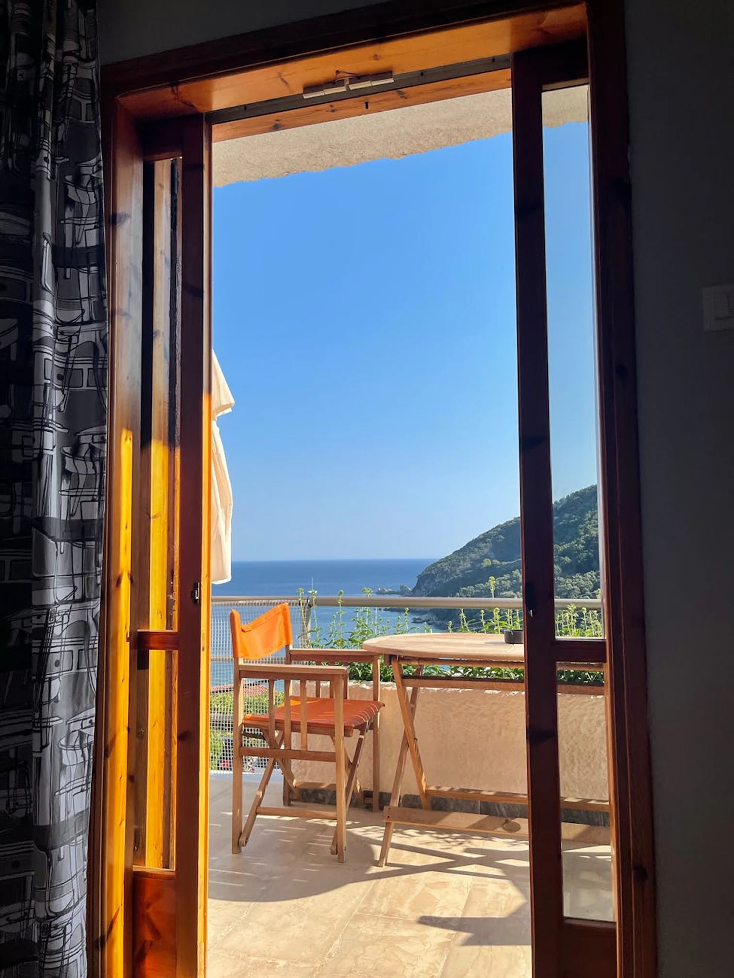 Open doorway leading to a private balcony with chairs and an ocean view.