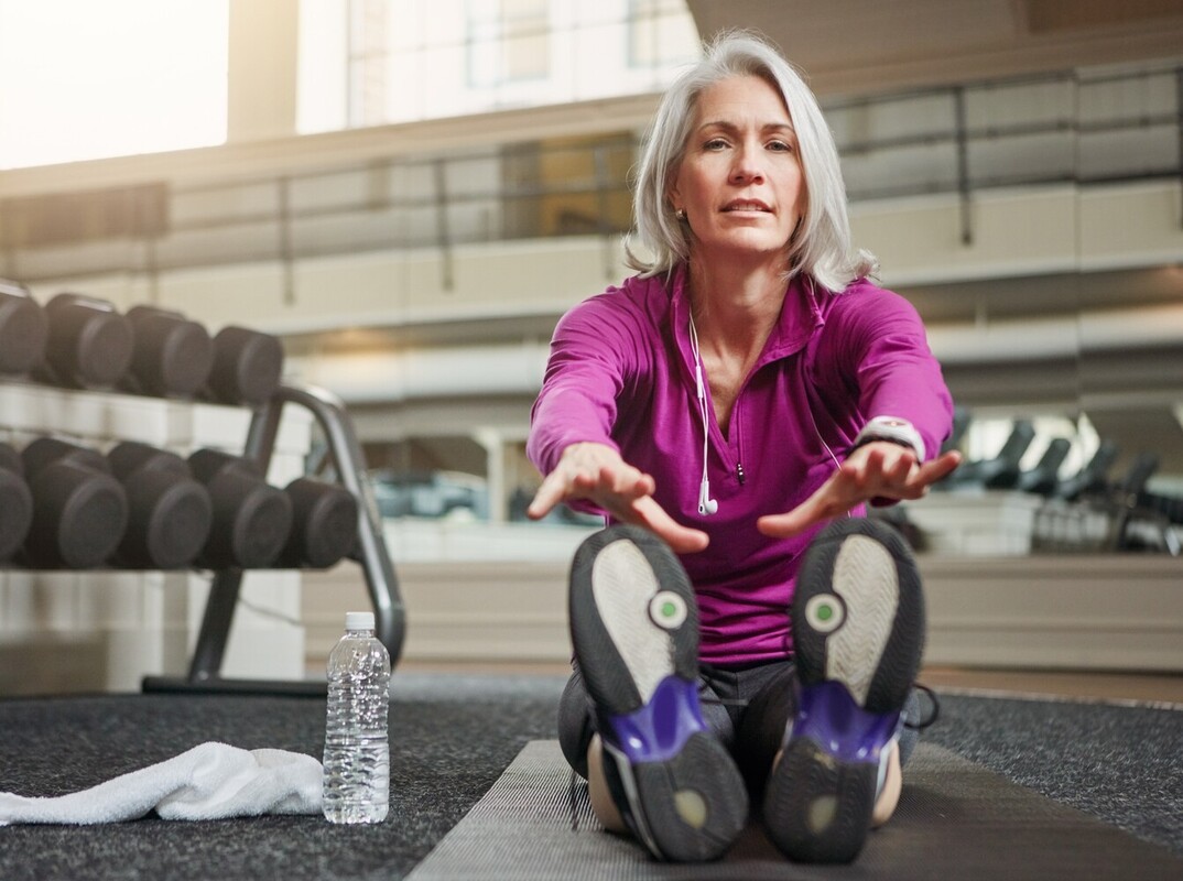 older woman doing mobility work at the gym to support her weight loss from walking